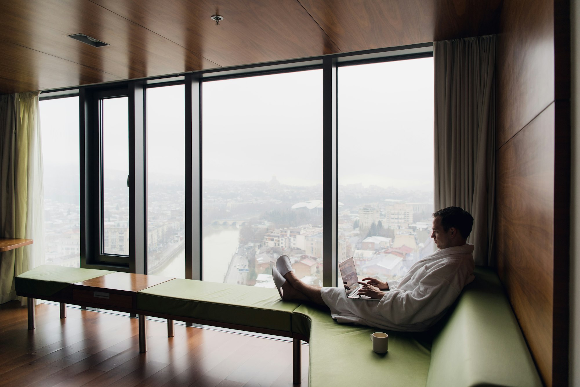 Attractive Man enjoying his morning coffee on his computer at his hotel room