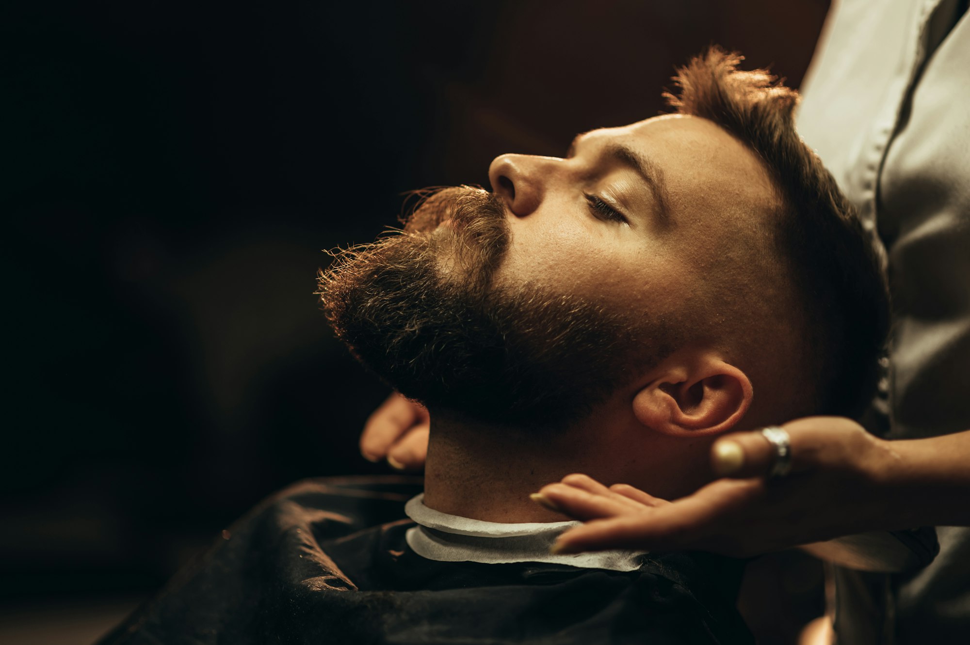 close shot of a young man beard while he is sitting at a barbershop