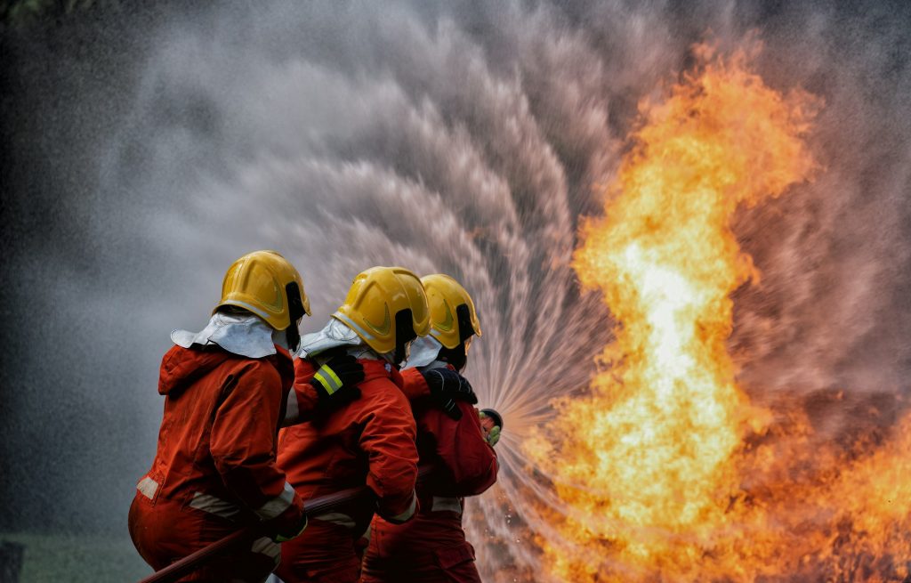 fire fighter team on training with gas and oil fire hold hose spray jet water spray to extinguish