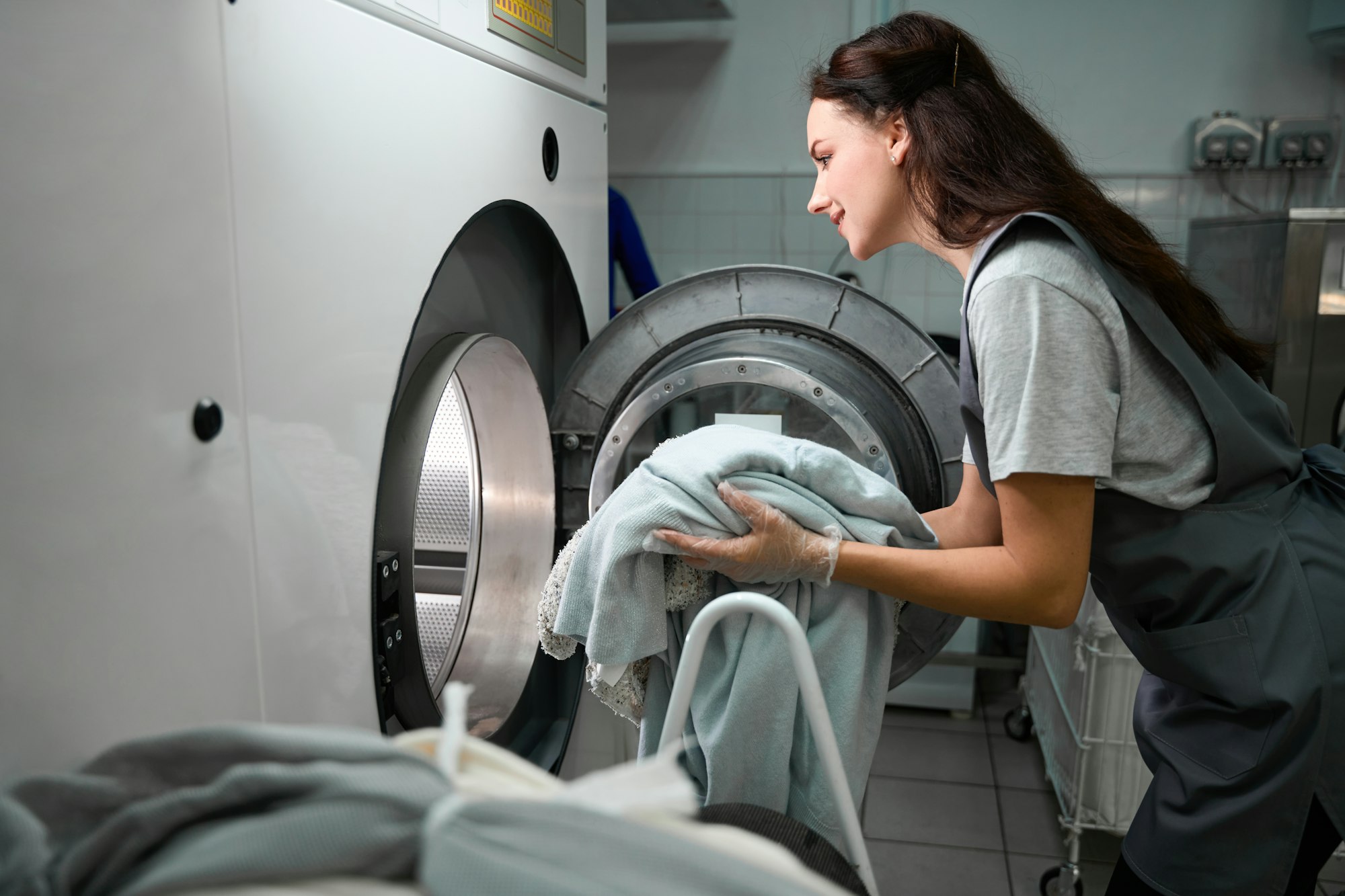 dry cleaner worker loading drum machine with sorted clothes