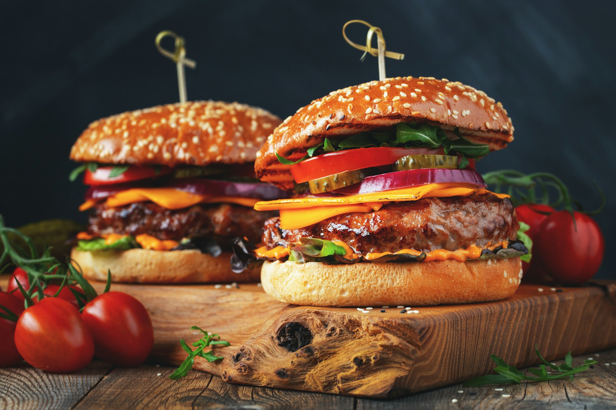 two delicious homemade burgers of beef cheese and vegetables on an old wooden table