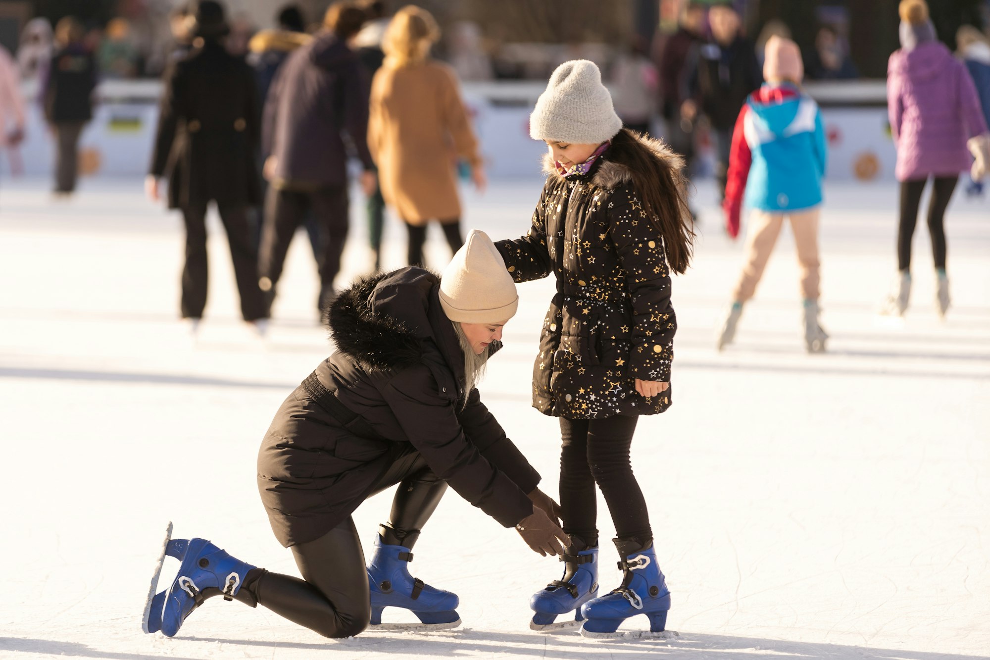 Mother with her daughters skates on ice skating